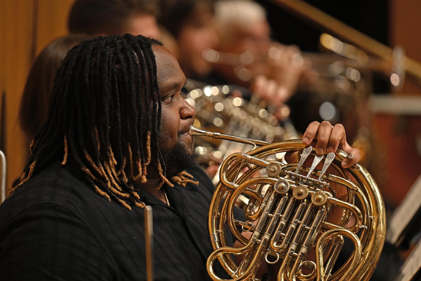 An orchestra member playing the French Horn.