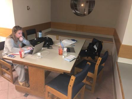 Lexi's friend molly sits at a table in the Plex with her laptop and study material out.