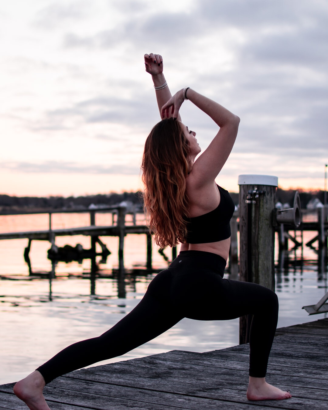 Lexi Pope does Buti Yoga on a dock in the settings sun