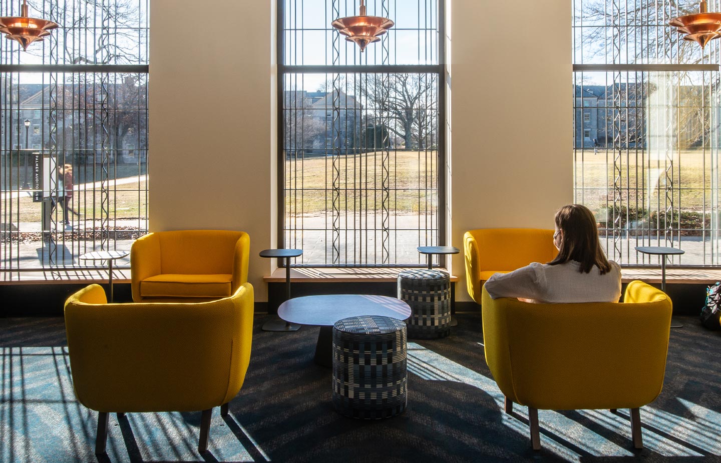 Student looking out of the green-side windows of the new Athey Center