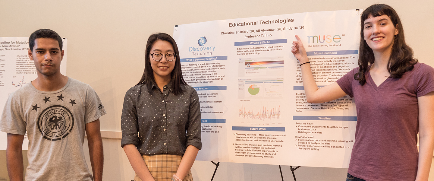 Three students pose next to the poster detailing their science research. 