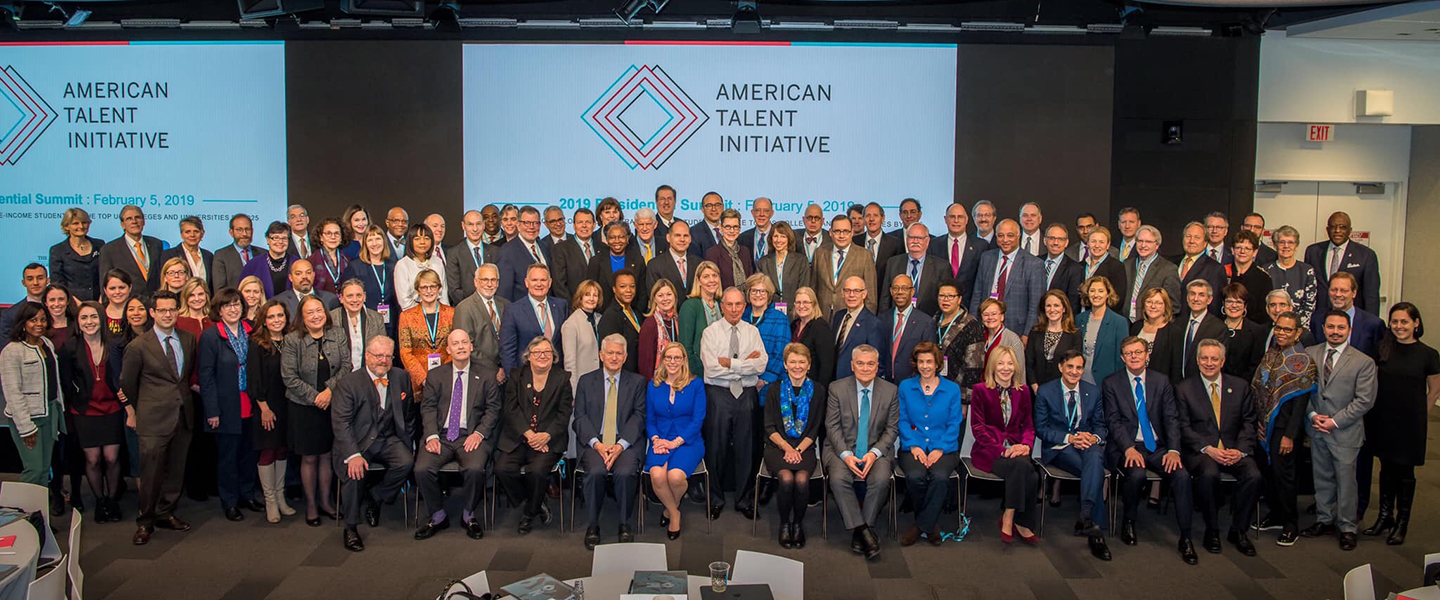 A large group of people pose in front of the ATI logo.