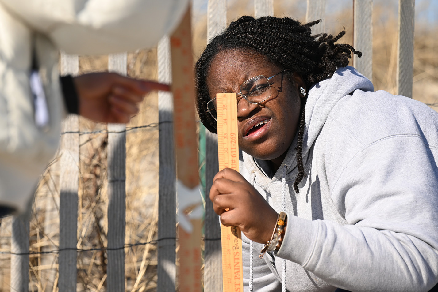 Libby Kotei-Fearon ’26 sights off a meter stick to measure the slope of the beach and track the effects of sea level rise during a research trip to Waterford Town Beach in February.