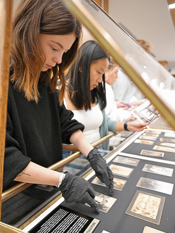 Mia Webb ’24, left, and Hannah Treiber ’26 arrange photographs in a display case.