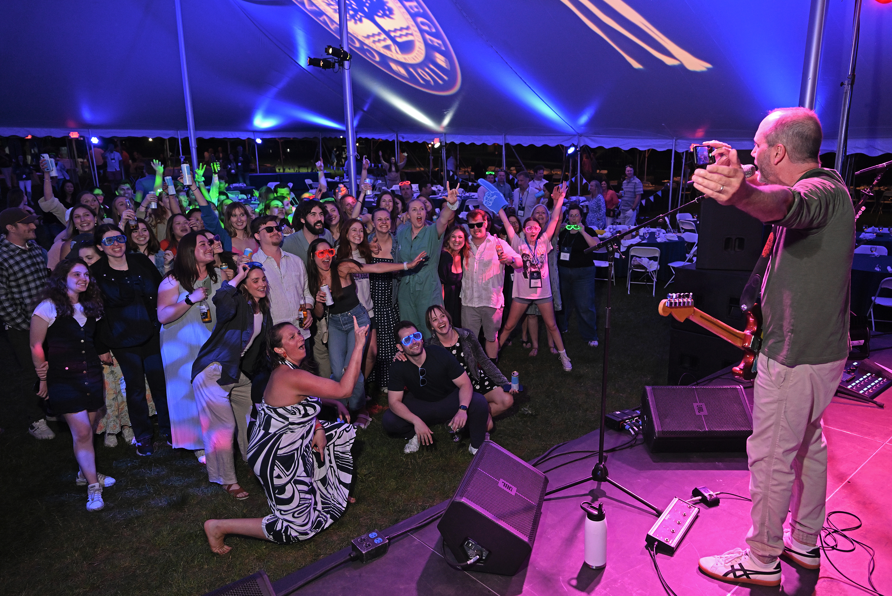 College alumni gather for a group photo during a concert.