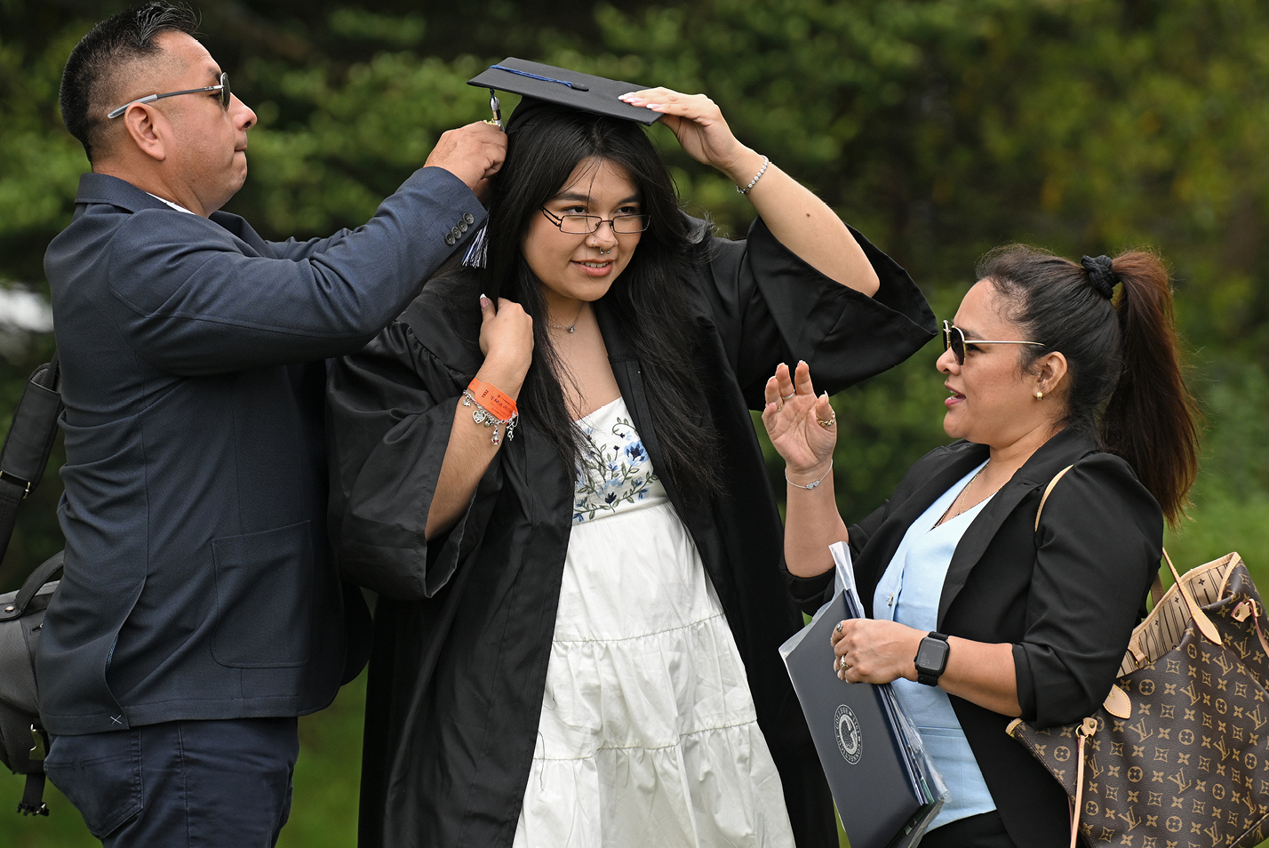 A student gets help with a cap.