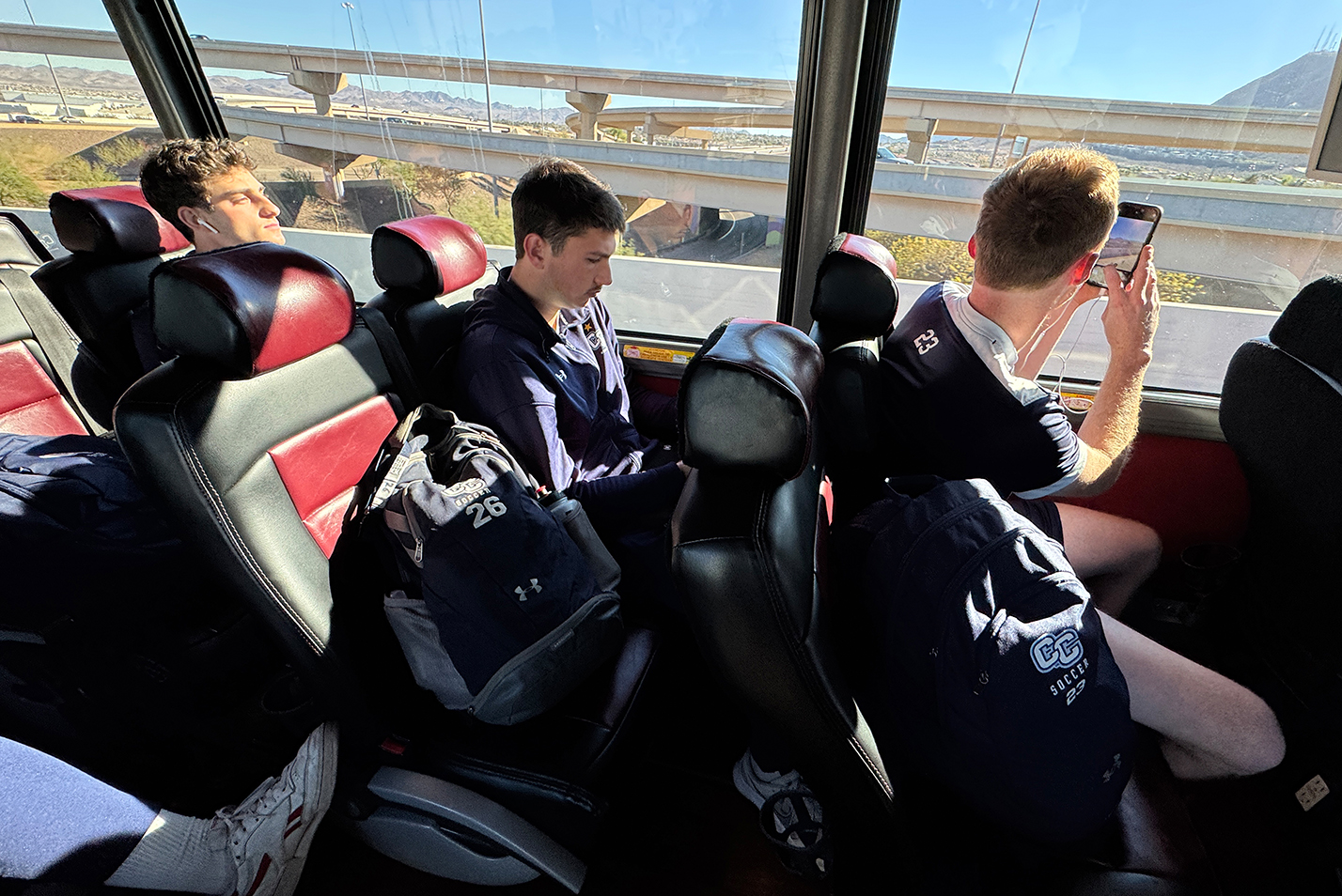 Soccer players riding a bus take photos of the scenery passing by.