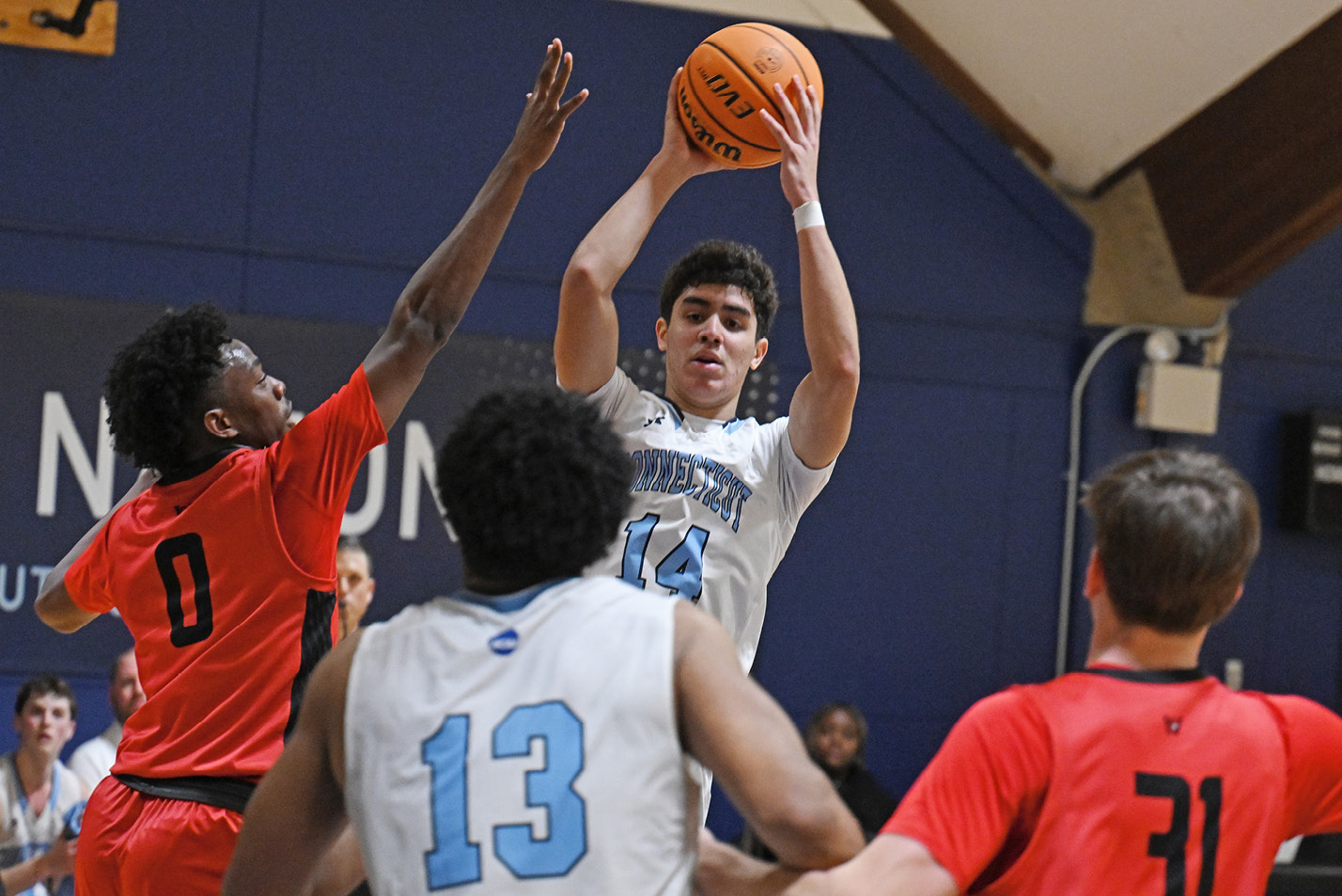 Connecticut College men's basketball forward Elias Espinosa '26 leaps over Wesleyan defenders