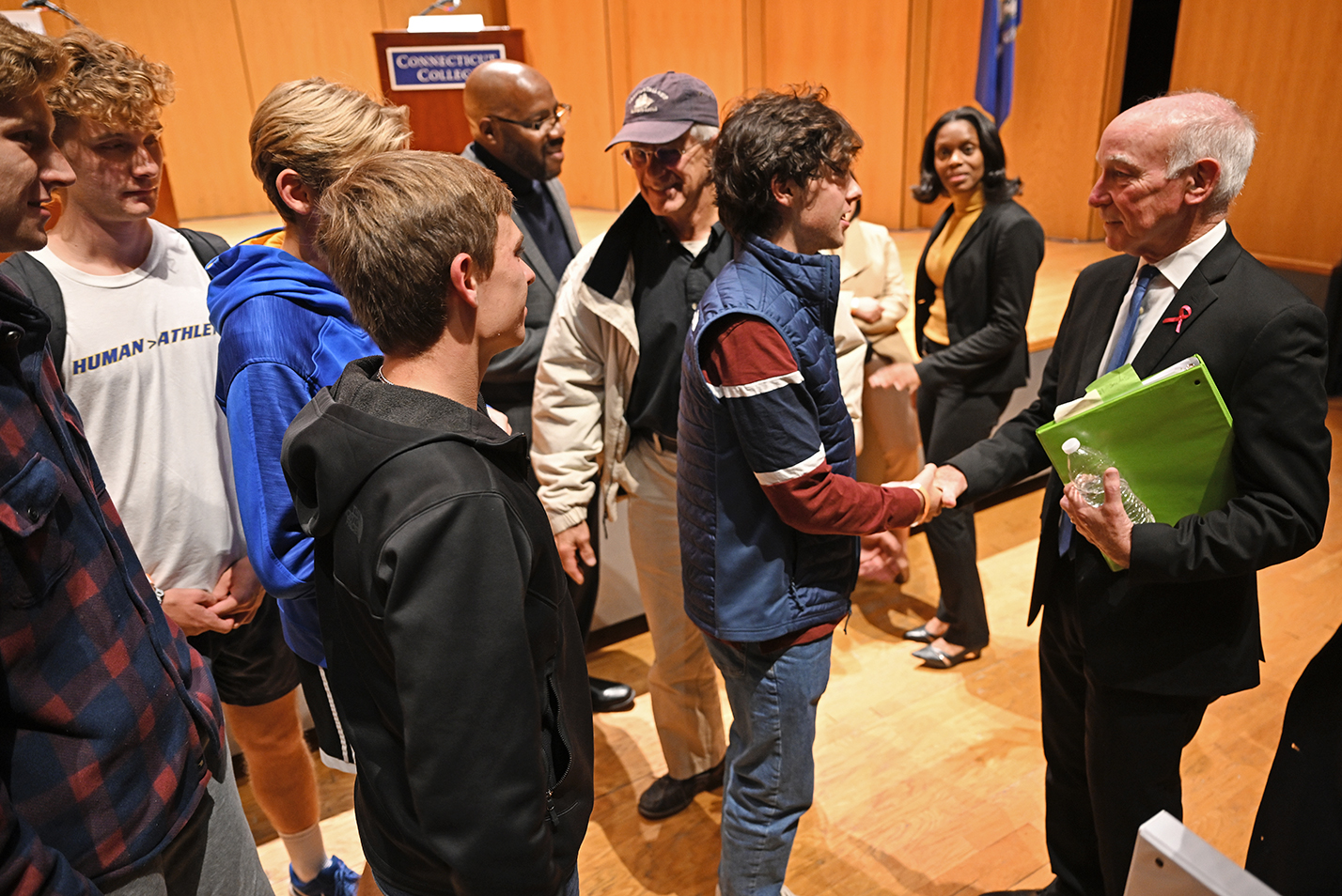 A congressman shakes hands with students after a debate on campus.