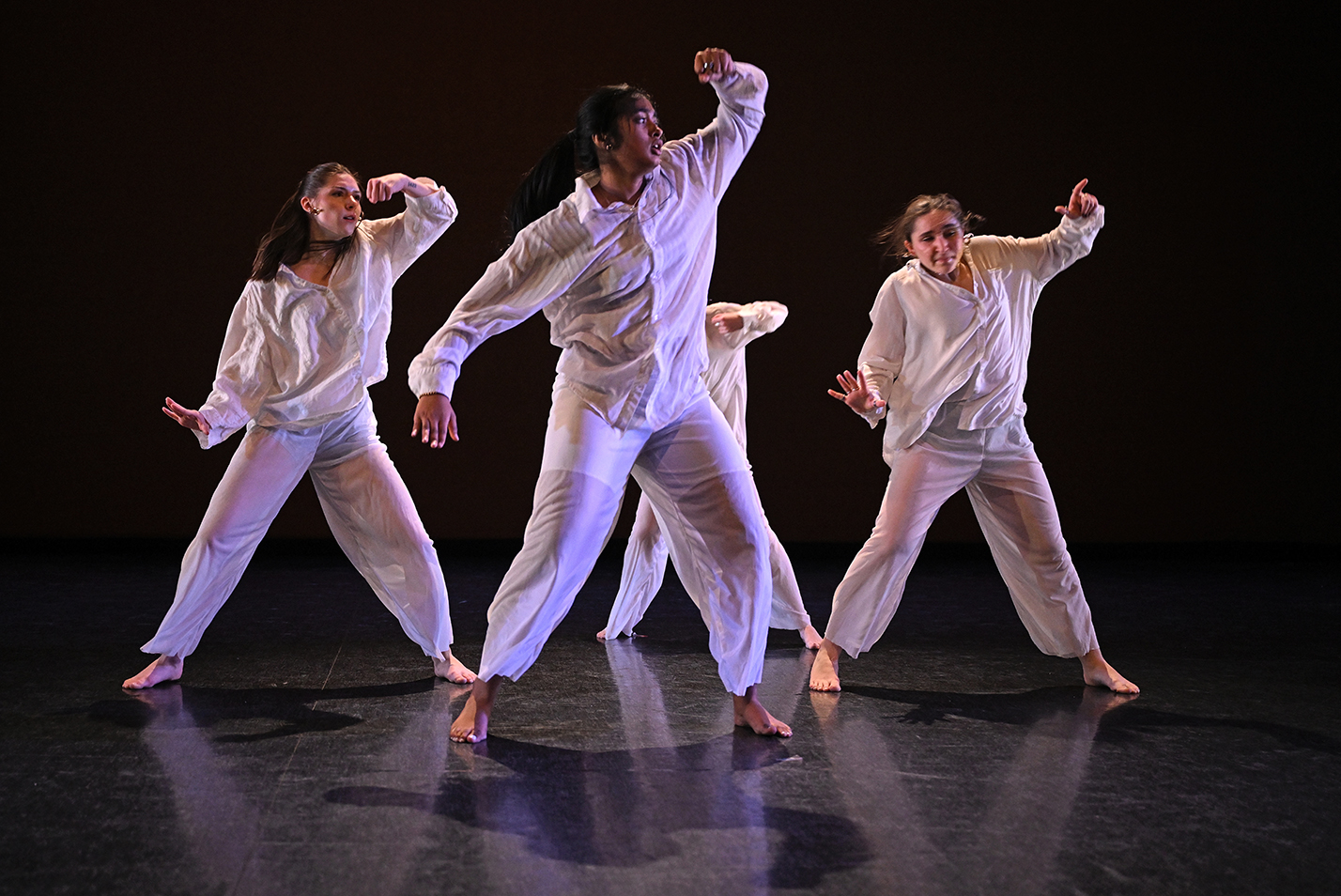 Four dancers in all-white perform a modern dance.