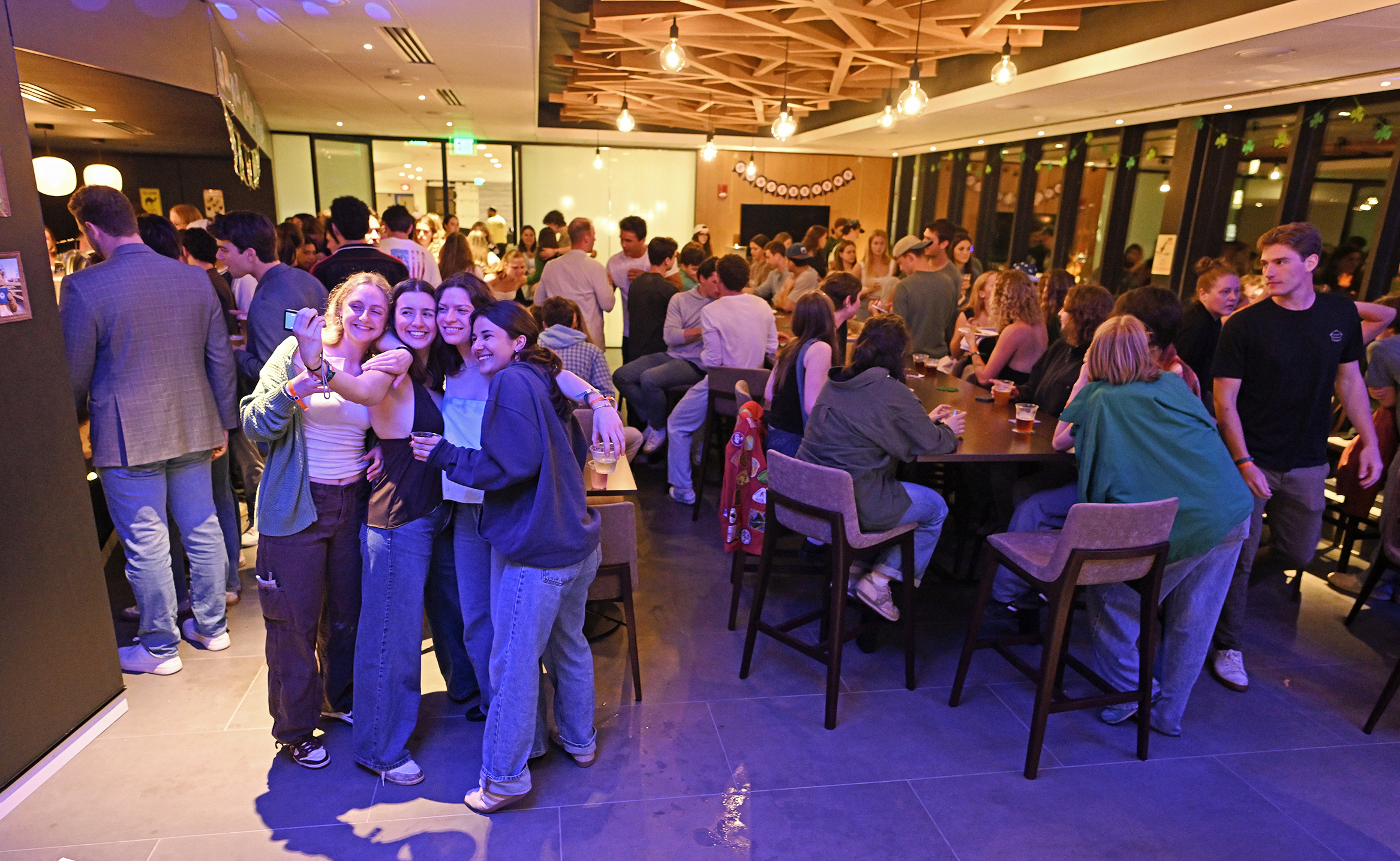 Students take photos together as they enjoy a pub night gathering in a newly renovated space in the student center.