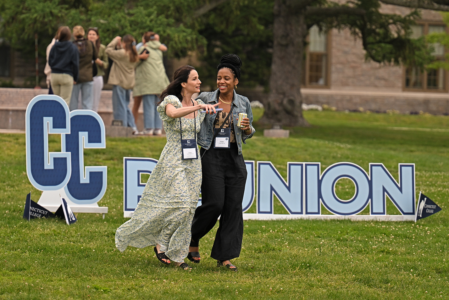 People walk past a sign for a college reunion on the campus green.