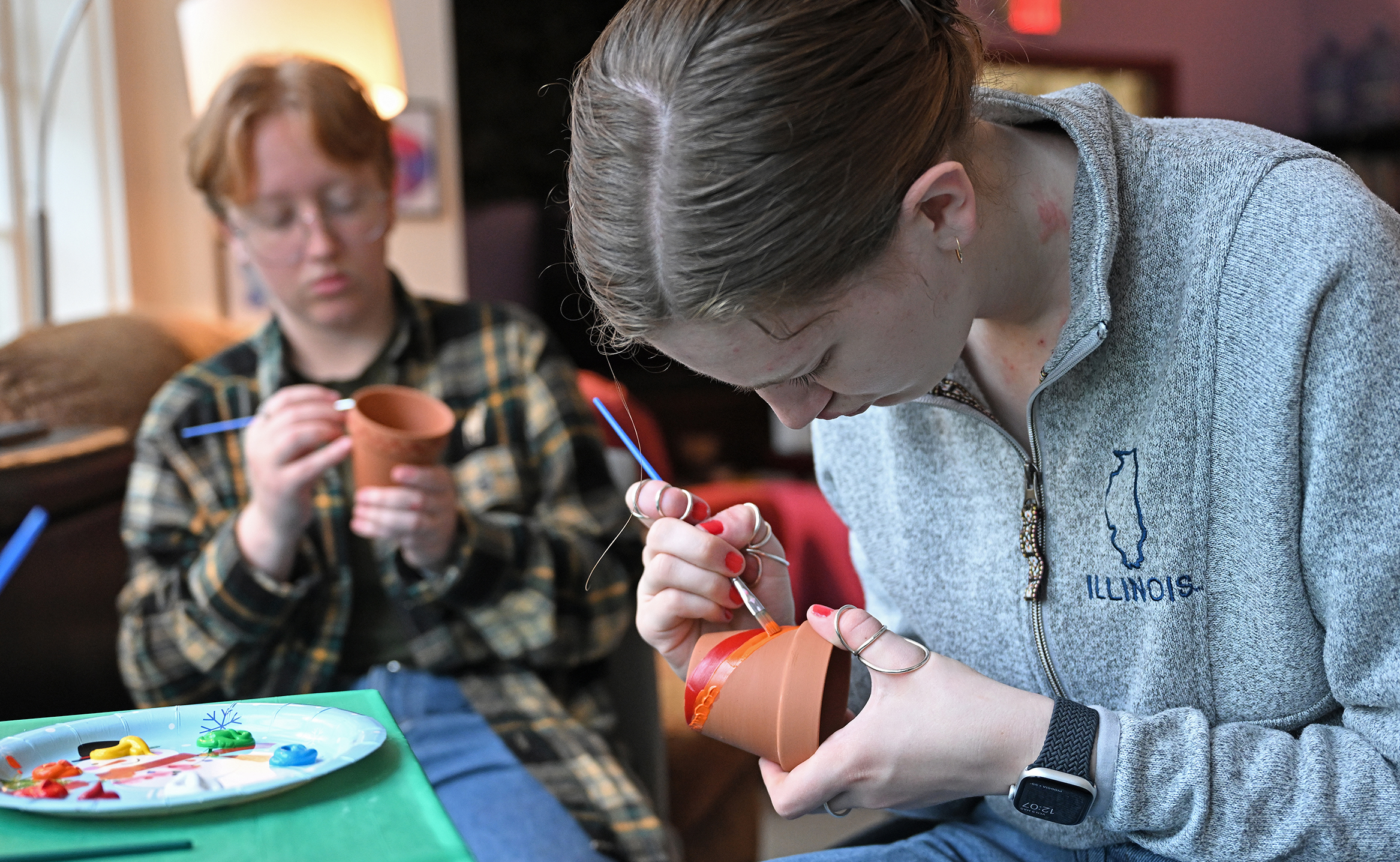 Two students paint terra cotta plant pots.