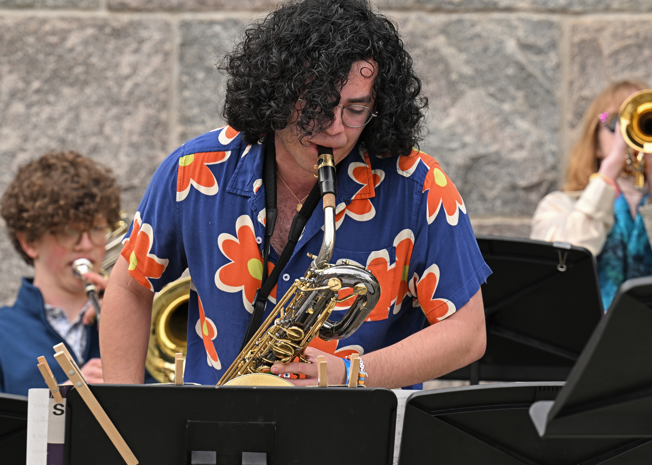 student in a tropical shirt playing the bass saxophone